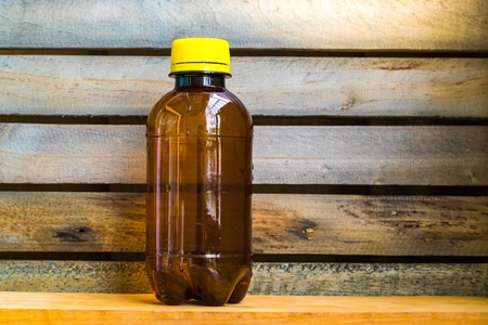 Bottle made to plastic and notepad on the wood with wall background. Using wallpaper for package or product and drug image.の写真素材