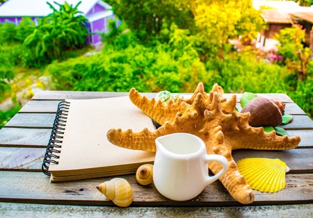 Notepad with pencil and starfish, shellfish on wood background.using wallpaper for education, business photo. Take note of the product for book with paper concept or copy space and refreshing.の写真素材