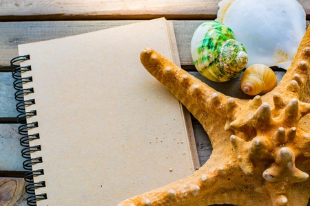 Notepad with pencil and starfish, shellfish on wood background.using wallpaper for education, business photo. Take note of the product for book with paper concept or copy space and refreshing.の写真素材