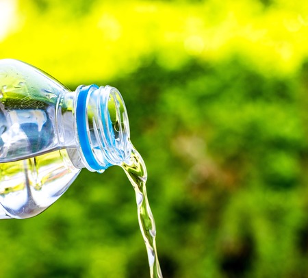 Bottle  water made to plastic on the wood and tree blurry bokeh background in garden. Using...