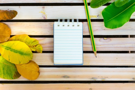 Notepad with pencil on wood board background. using wallpaper or background for education, business...
