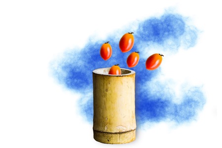 Bamboo cylinder with tomato on the wood background.Using wallpaper for package or product with concept, advertising and refreshing image.の写真素材