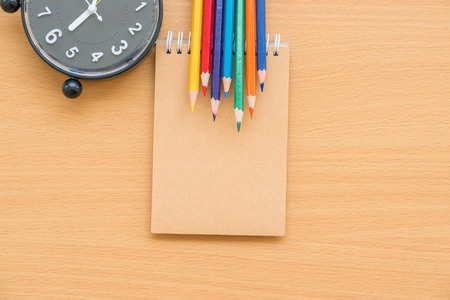 Notepad with clock on wood board background. using wallpaper or background for education, business photo. Take note of the product for book with paper and concept or copy space and note.の写真素材