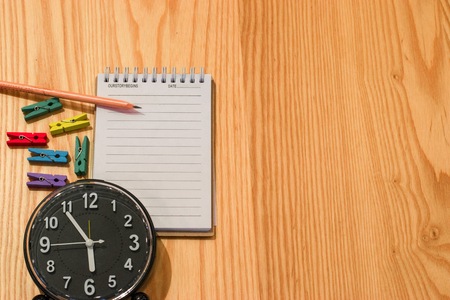 Notepad with clock on wood board background. using wallpaper or background for education, business photo. Take note of the product for book with paper and concept or copy space and note.の写真素材