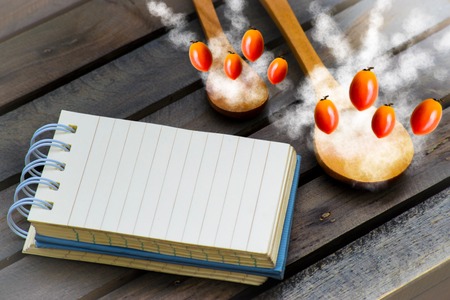 Notepad with spoons and vegetable on wood wood background.Using wallpaper for food, kitchen and cook composition image Take note product for book with paper and concept or copy space with note and advertising.の写真素材