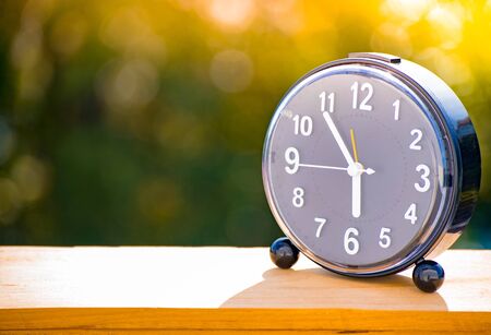 Notepad with clock on wood board tree blurry background. using wallpaper or background for...
