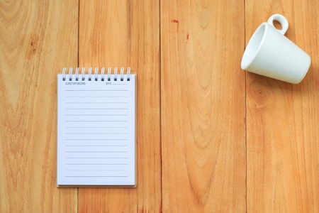 notepad with cup or glass and spoon on wood board background.using wallpaper or for education,...