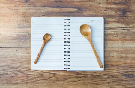Notepad with spoon on wood board background.using wallpaper for education, business photo.Take note of the product for book with paper and concept or copy space.の写真素材