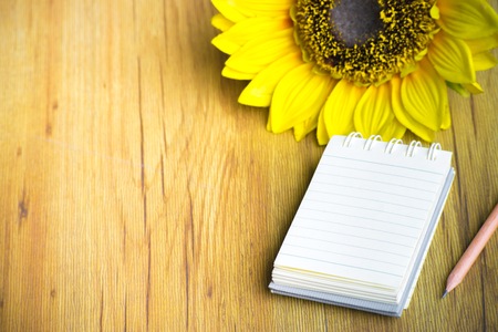 Notepad with sun flower on wood board background.using wallpaper for education, business photo.Take note of the product for book with paper and concept or copy space.の写真素材