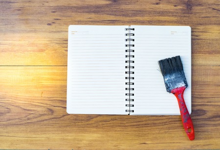 Notepad with paint brush on wood board background.using wallpaper for education, business photo.Take note of the product for book with paper and concept or copy space.の写真素材