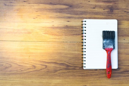 Notepad with paint brush on wood board background.using wallpaper for education, business photo.Take note of the product for book with paper and concept or copy space.の写真素材