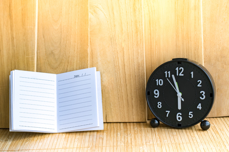 Notepad with pencil and clock on wood board background.using wallpaper for education, business photo.Take note of the product for book with paper and object, concept or copy space.の写真素材