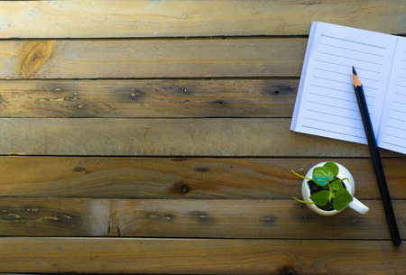 Notepad with pencil and tree in pot on wood board background.using wallpaper for education, business photo.Take note of the product for book with paper and concept, object or copy space.の写真素材