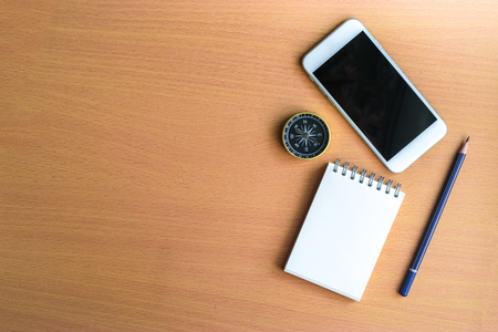 Notepad with pencil, compass and smart phone on wood board background.の写真素材