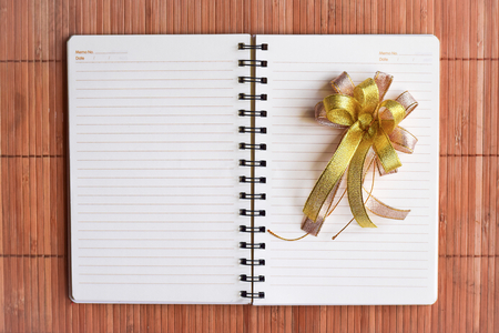 Notepad with gift and ribbon on wood board background.using wallpaper for education, business photo.Take note of the product for book with paper and concept, object or copy spaceの写真素材