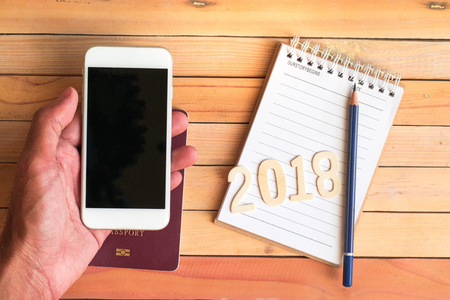 Notepad with smartphone and num 2018 on wood board background.using wallpaper for education, business photo.Take note of the product for book with paper and concept, object or copy space.の写真素材