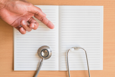 Notepad with stethoscope and pencil on wood board background.using wallpaper for education, business photo.Take note of the product for book with paper object, concept or copy space.の写真素材