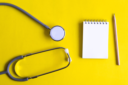 Notepad with stethoscope and pencil on wood board background.using wallpaper for education, business photo.Take note of the product for book with paper object, concept or copy space.の写真素材