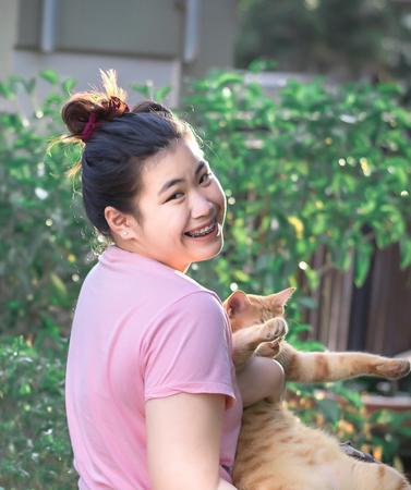 Asian women playing with cat on tree bokeh blurry background.Using wallpaper or background for animal, happiness, friendship image.の写真素材