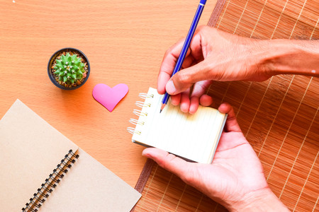 Notepad with pencil and cactus in a pot on wood background.using wallpaper for education, business photo.Take note of the product for book with paper and concept, object or copy space.の写真素材