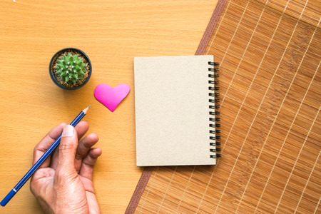 Notepad with pencil and cactus in a pot on wood background.using wallpaper for education, business photo.Take note of the product for book with paper and concept, object or copy space.の写真素材