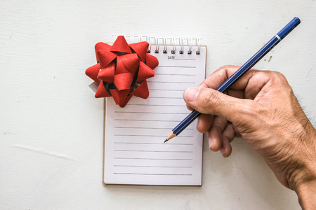 man writing notepad gift box and pencil on desk wood  background.using wallpaper for education, business photo.Take note of the product for book with paper and concept, object or copy spaceの写真素材
