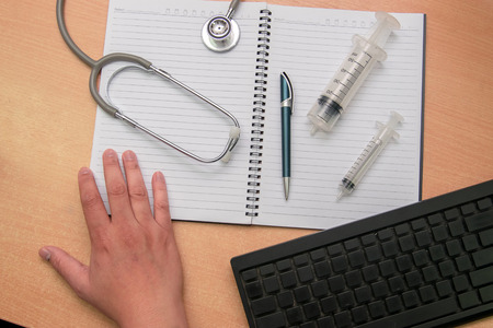 Notebook, pen with Smartphone, Injection and Medical Headphones stethoscope on table. For medical...