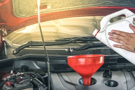 man pouring engine oil with blurred engine background.For automotive, transportation maintenance image.の写真素材