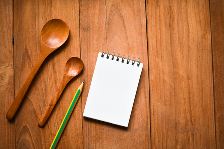 Notepad with pencil and spoon on wood board background.using wallpaper for education, business photo.Take note of the product for book with paper and concept, object or copy space.の写真素材