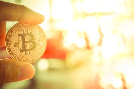 Asian man business holding tecnology bit coin in blurry office background. For business people, finance, lifestyle and ethereum or block chain tecnology imageの写真素材