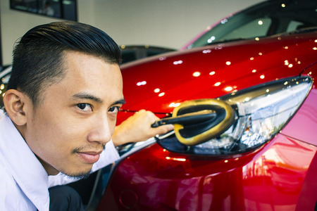Asian man is wipping car with LED headlight for customers.Using 
wallpaper or background for transportation and automotive image.の写真素材