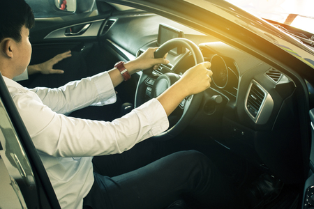 man asian driving car on blurry background in showroom. Using wallpaper 
for transport, automotive automobile and car for advertising image.の写真素材