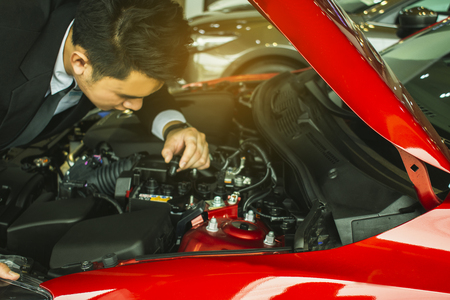 Asian businessman with engine on blurred background.For automotive or Maintenance, service or...