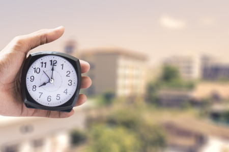 Holding clock on city blurred background The time 8:00 am or pm and noon or midnight for made clock...