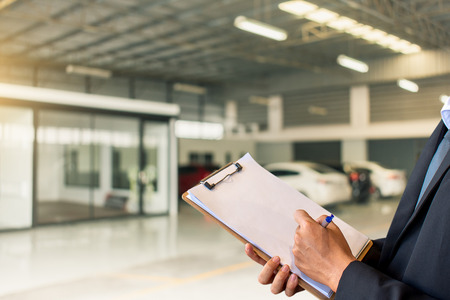 This career man saleman business inspection writing note on notepad or
book, paper with car blurry background.for transport automobile
automotive image.の写真素材
