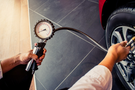 Asian man car inspection Measure quantity Inflated Rubber tirescar.Close up hand holding machine Inflated pressure gauge for car tyrepressure measurement for automotive, automobile imageの写真素材
