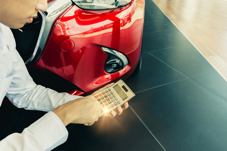 This career salesman calculating on calculator car price in showroomcar.Close up tire red car in dealership transport automobile industryinspection business automotiveの写真素材