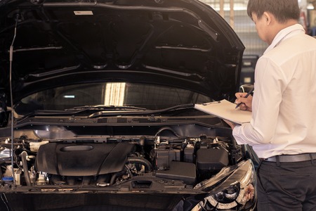 This career man saleman business inspection writing note on notepad or book, paper with car blurry background.for transport automobile automotive image.の写真素材