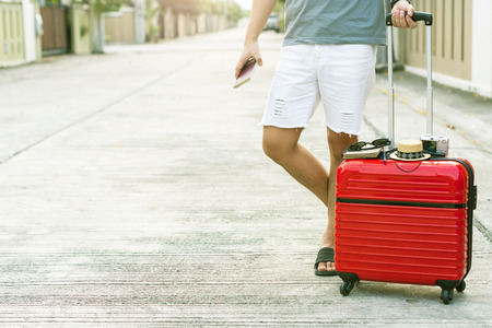 Man holding Red luggage with passport on blurred city background 
for activity lifestyle outdoors freedom or travel tourism 
andinspiration backpacker alone tourist imageの写真素材