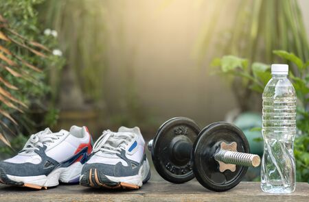 Sports shoes  with dumbbell weights and bottle on tree blurred background.Metaphor Fitness and workout concept exercise Health lifestyle muscle with  take care of your health copy for advertisingの写真素材
