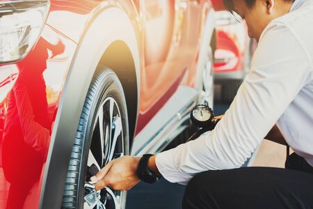 Asian man car inspection Measure quantity Inflated Rubber tires car.Close up hand holding machine Inflated pressure gauge for car tyre pressure measurement for automotive, automobile imageの写真素材