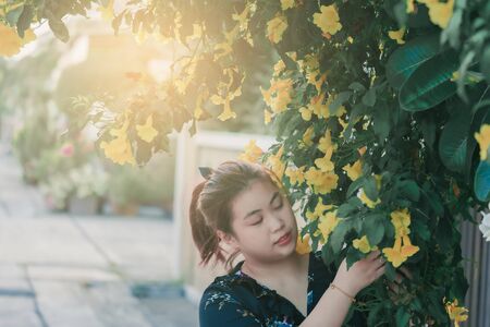Asian woman with yellow flower and green leaves or leaf blurred background for lifestyle portrait people imageの写真素材