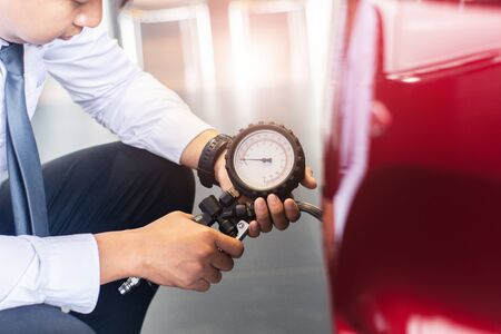 Asian man car inspection Measure quantity Inflated Rubber tires car.Close up hand holding machine...