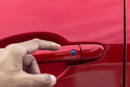 Asian man opens red car door with smart keyless For automotive or transportation imageの写真素材
