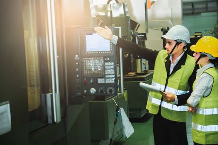 Asian female engineer factory inspection with man business engineer in industry She wears a helmet female working metalwork control in industrial In a plastic factory for carの写真素材