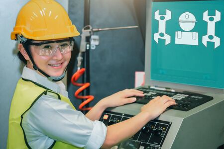Asian female engineer factory inspection computer control with robot ai machine assist production engineer in industry She wears a helmet female working metalwork control in industrial plastic factory for carの写真素材