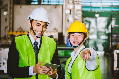 Asian female engineer factory inspection with man business holding tablet 
engineer in industry We wears a helmet female working metalwork control in industrial In 
a plastic factory for carの写真素材