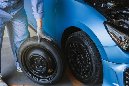 Asian man car inspection Measure quantity Inflated Rubber tires car.Closeup hand holding tire and blue car for tyre pressure measurement for automotive, automobile Car industry imageの写真素材