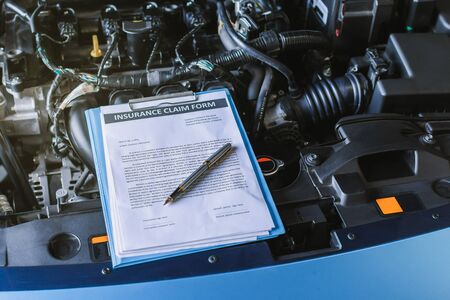 Asian Man mechanic inspection writing note on clipboard.Blue car for service maintenance insurance with car engine.for transport automobile automotive image.の写真素材