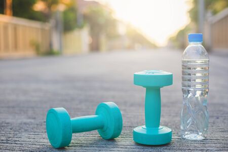 dumbbell weights and bottle on street blurred background.Metaphor Fitness and workout concept exercise Health lifestyle muscle with  take care of your health copy for advertisingの写真素材